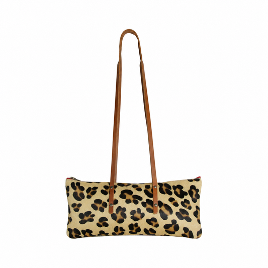 Sac Le Baguette en cuir à poils, motif léopard, avec ses anses cognac fixées sur la face du sac, vu de face sur fond blanc.