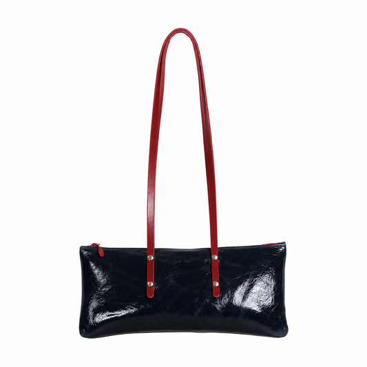 Sac Le Baguette en vachette velours brillant bleu nuit, avec ses anses rouges fixées sur la face du sac, vu de face sur fond blanc.