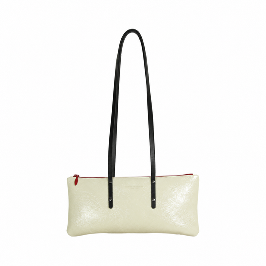 Sac Le Baguette en vachette velours brillant ivoire, avec ses anses noires fixées sur la face du sac, vu de face sur fond blanc.