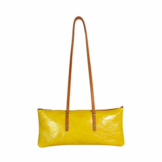Sac Le Baguette en vachette velours brillant jaune, avec ses anses cognac fixées sur la face du sac, vu de face sur fond blanc.