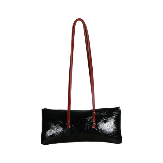 Sac Le Baguette en vachette velours brillant noir, avec ses anses rouges fixées sur la face du sac, vu de face sur fond blanc.
