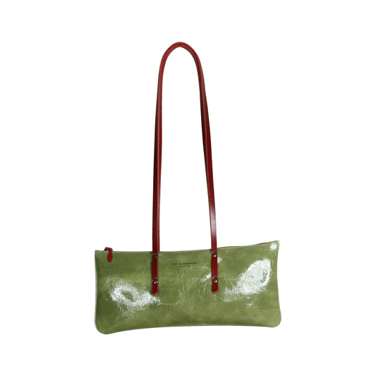 Sac Le Baguette en vachette velours brillant vert clair, avec ses anses rouges fixées sur la face du sac, vu de face sur fond blanc.
