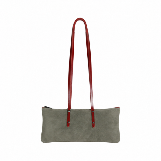 Sac Le Baguette en vachette velours gris, avec ses anses rouges fixées sur la face du sac, vu de face sur fond blanc.