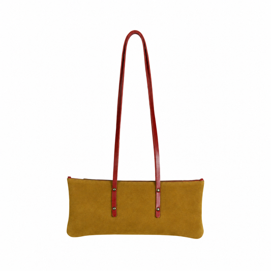 Sac Le Baguette en vachette velours ocre, avec ses anses rouges fixées sur la face du sac, vu de face sur fond blanc.